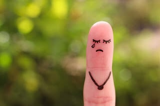 Finger with sad face drawn on it